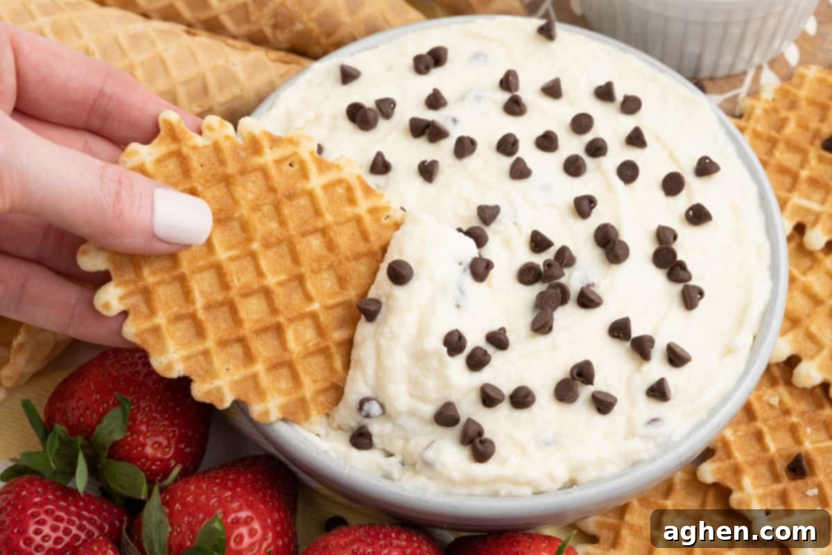 Waffle cookie being dipped into creamy ricotta and mascarpone cheese dip topped with chocolate chips, showcasing the perfect consistency of the best ricotta dip recipe.