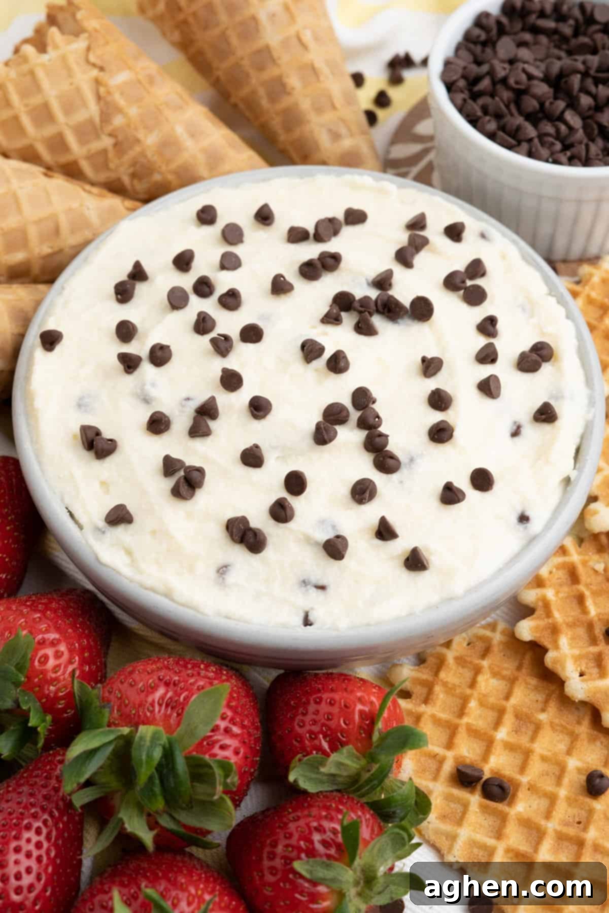 Cannoli dip with fresh strawberries, waffle cookies, and waffle cones for dipping, showcasing a beautiful dessert spread.
