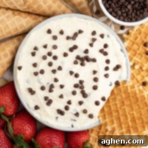 Cannoli dip with waffle cookie dipped into it, highlighting the deliciousness of this easy dessert.