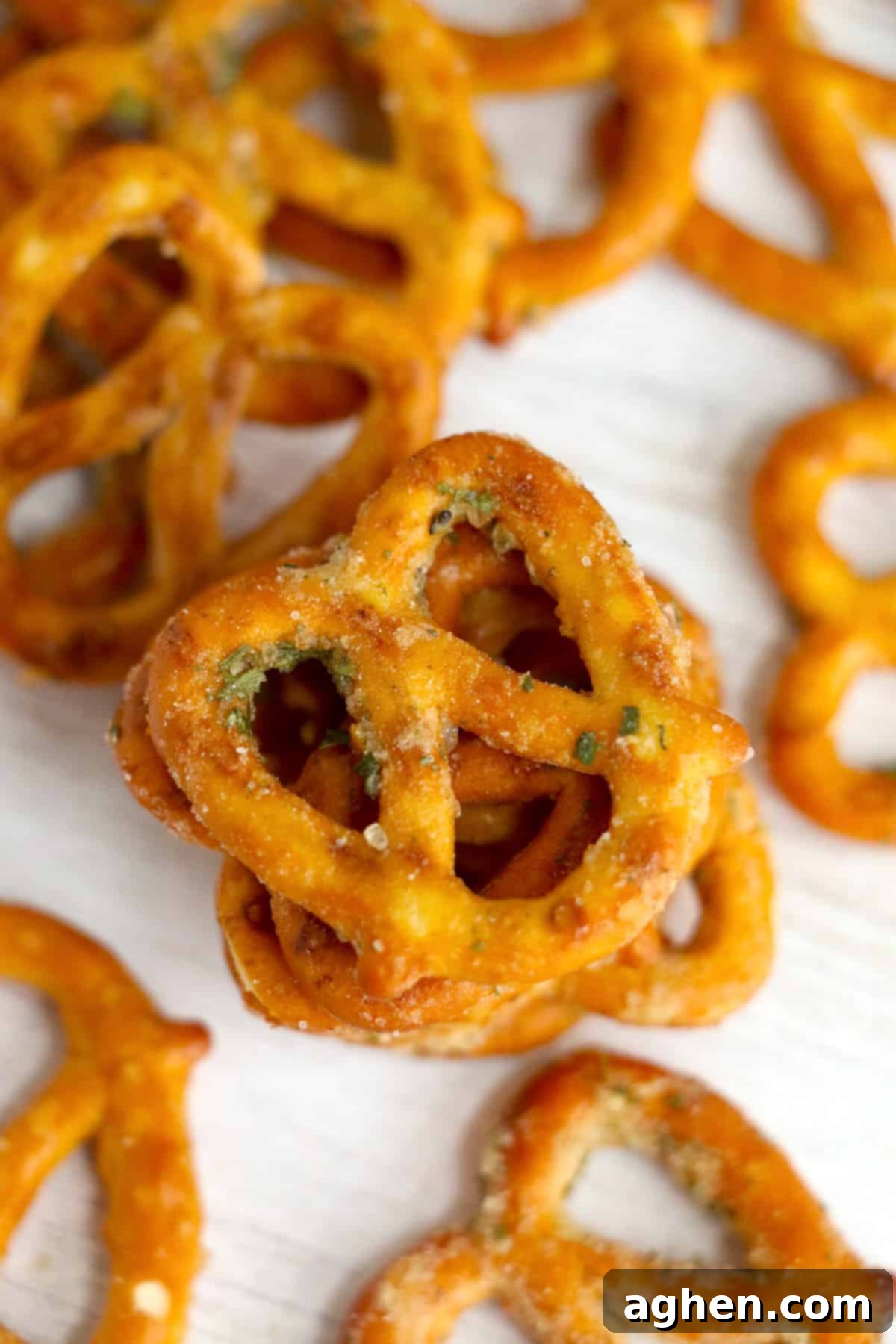 Numerous ranch and garlic seasoned pretzels scattered on a wooden table, inviting to be eaten.