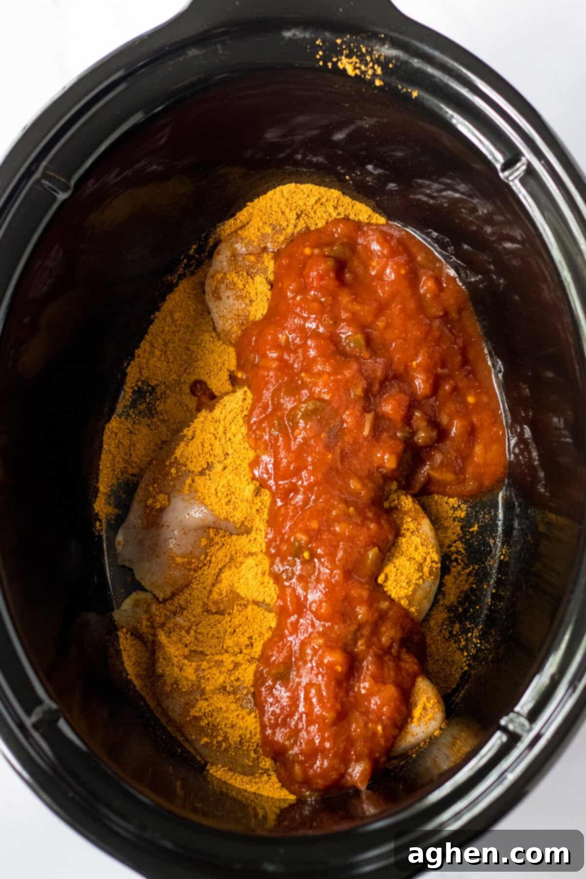 Chicken breasts in a crockpot topped with taco seasoning and salsa.