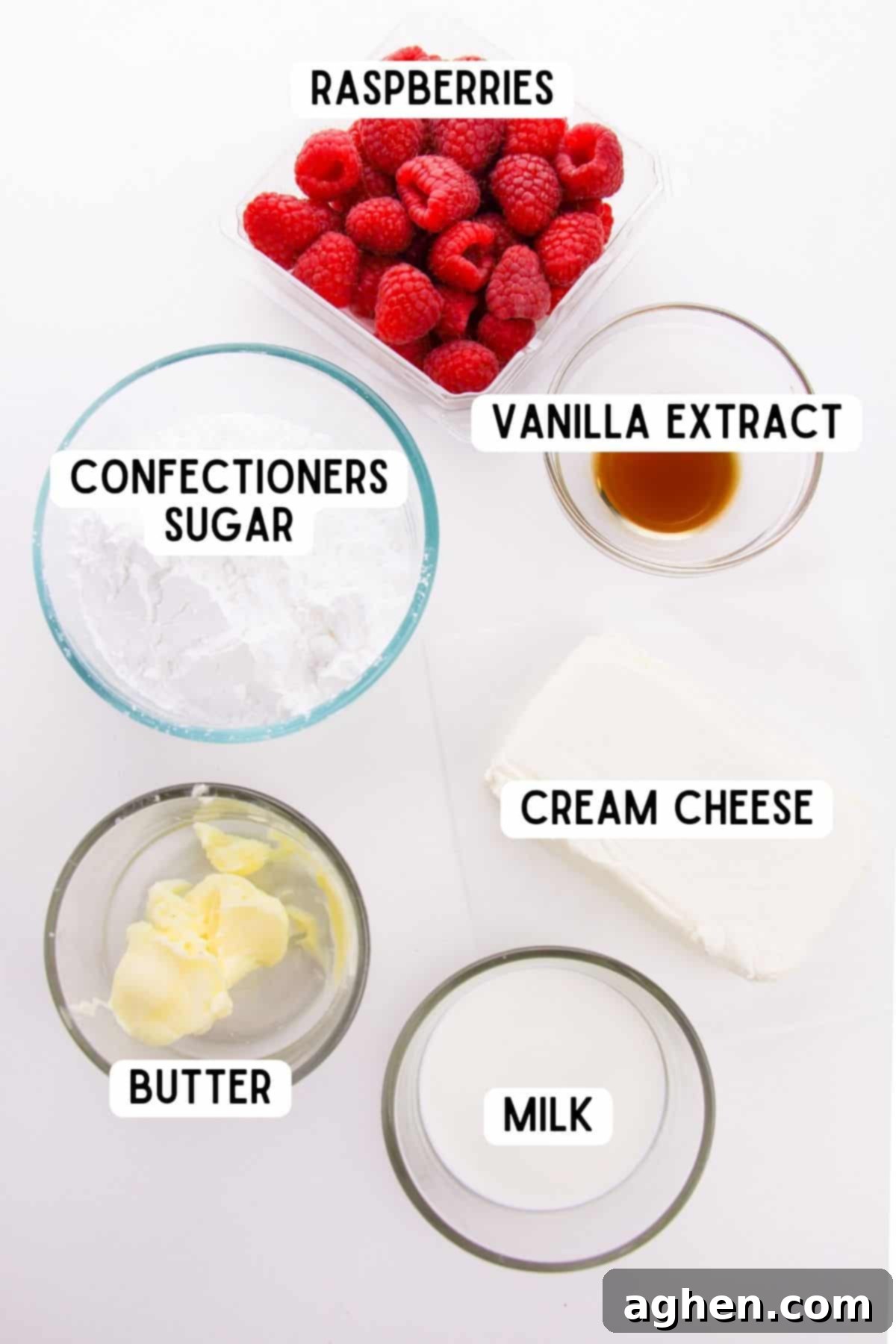 A flat lay photograph displaying all the fresh ingredients for raspberry dip: fresh raspberries, confectioners sugar, a block of cream cheese, milk, butter, and vanilla extract.