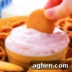 A small image of a bowl of raspberry cream cheese dip with a cookie being dipped.