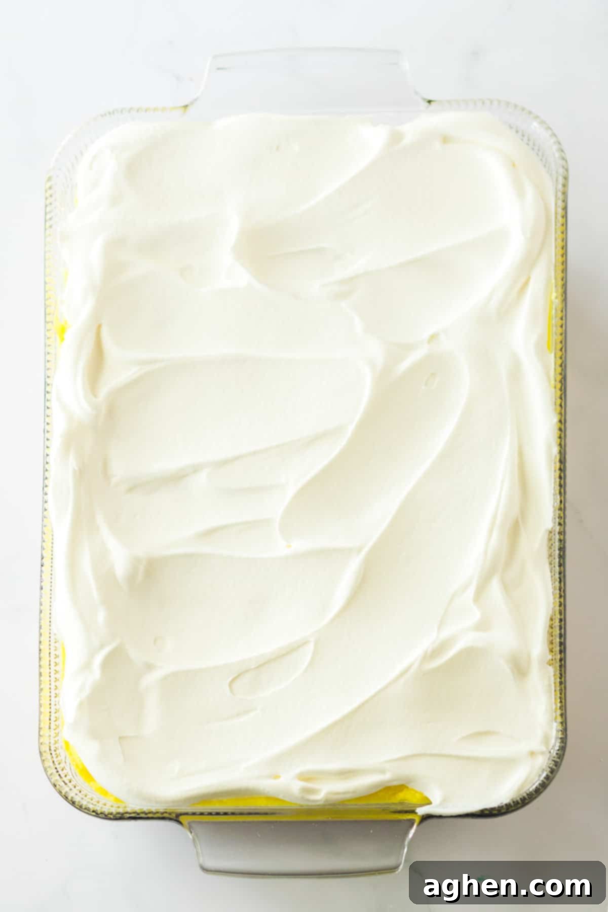 Ultimate No-Bake Banana Split 8 Whipped topping spread into an even layer in a rectangular glass dish.
