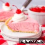 No-Bake Kool-Aid Dream Pie 13 Slice of cherry cool aid pie on white plate with large glass of milk in the background.