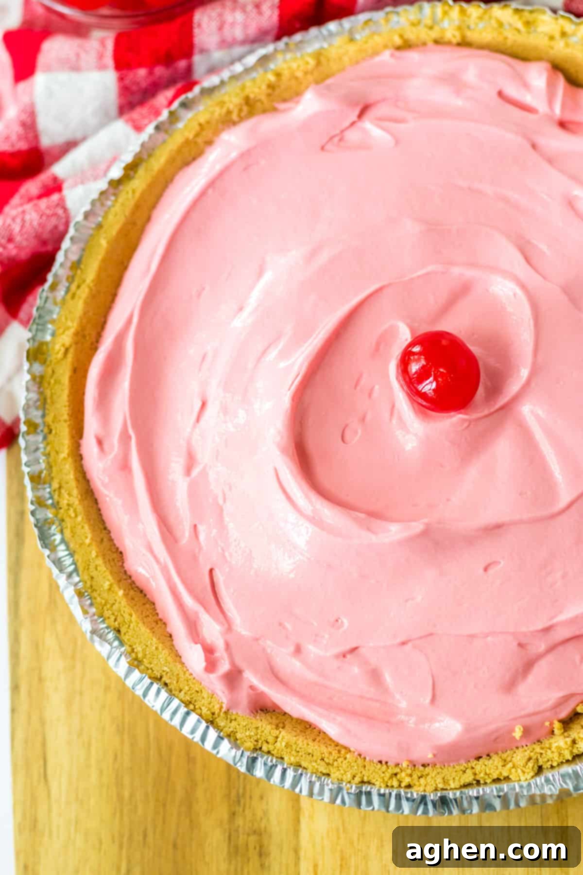 No-Bake Kool-Aid Dream Pie 3 Overhead photo of pink, creamy no bake kool aid pie in graham cracker crust with maraschino cherry in the center.