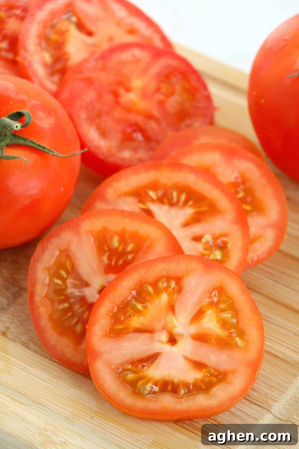 A perfectly sliced red tomato, cut into thick, even rounds on a rustic wooden cutting board, showcasing the ideal thickness for frying.