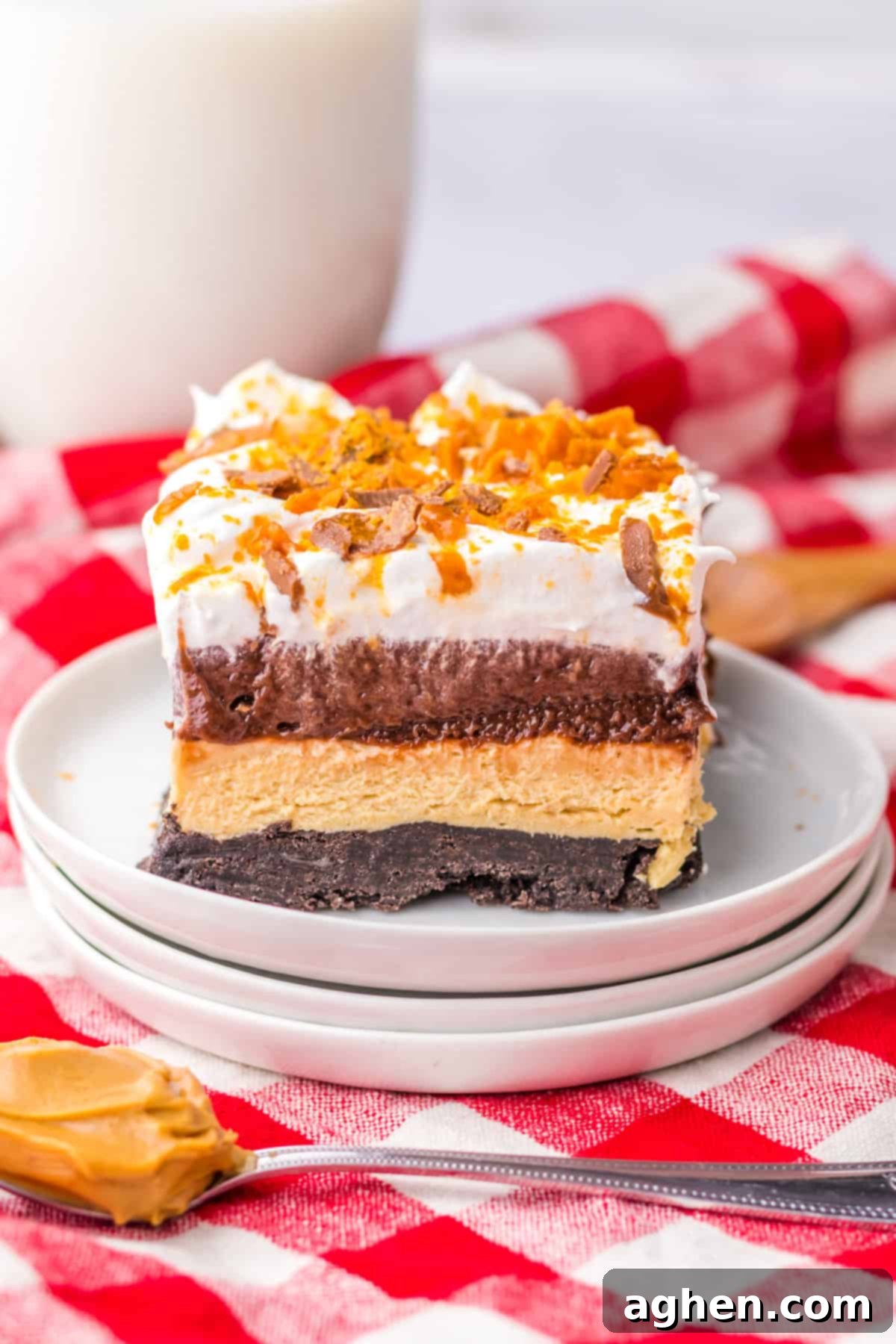 Butterfinger Crunch Layer Dream 2 A vibrant Butterfinger lush dessert, showcasing an Oreo cookie crust, smooth layers of no-bake peanut butter cheesecake, rich chocolate pudding, fluffy Cool Whip, and a generous topping of crushed Butterfingers.