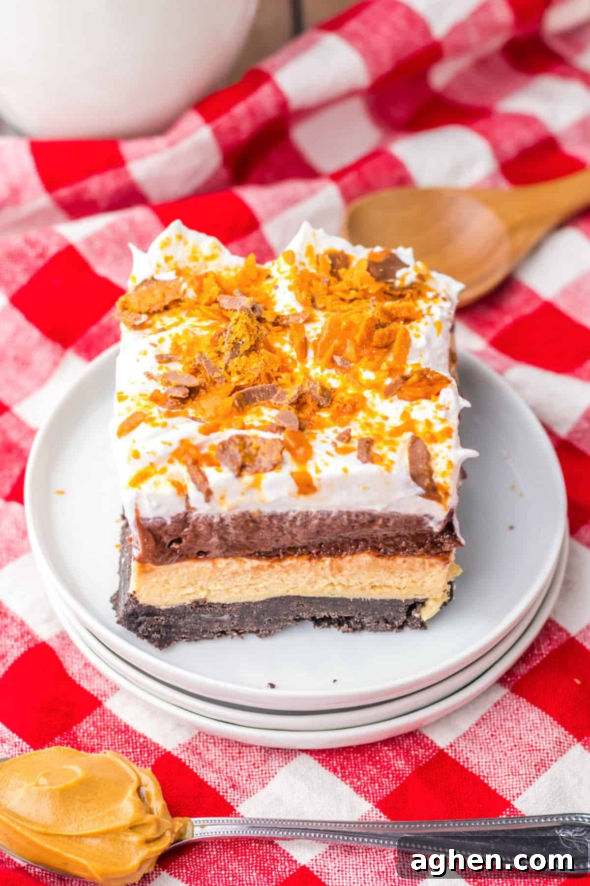 Butterfinger Crunch Layer Dream 6 A stunning Butterfinger delight layered dessert, generously topped with fluffy whipped topping and an abundance of crushed Butterfinger candy bars, ready to be served.