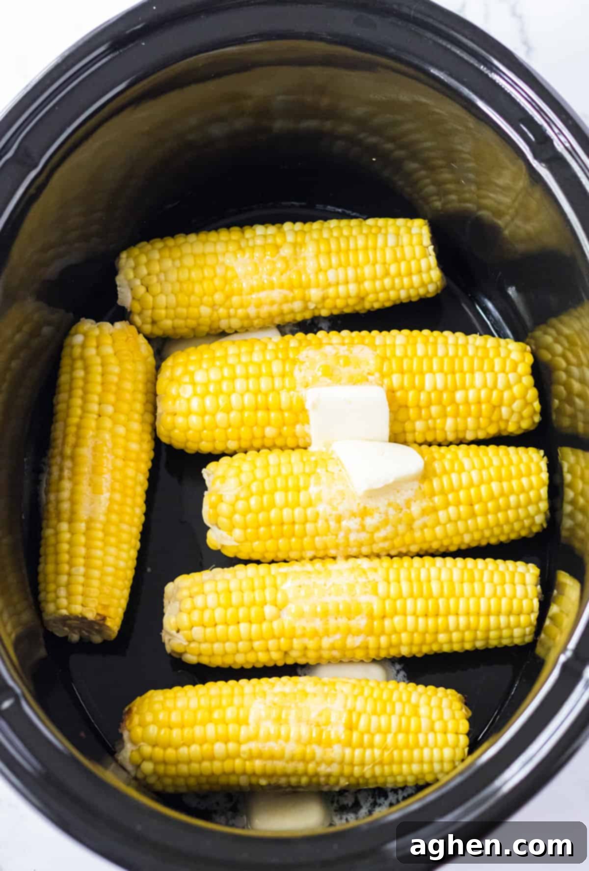 Effortless Slow Cooker Corn 6 Butter melting on top of corn in crock pot.