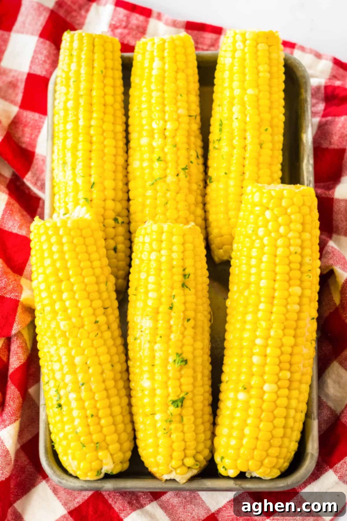 Effortless Slow Cooker Corn 8 Slow cooked corn on the cob served on a metal tray.