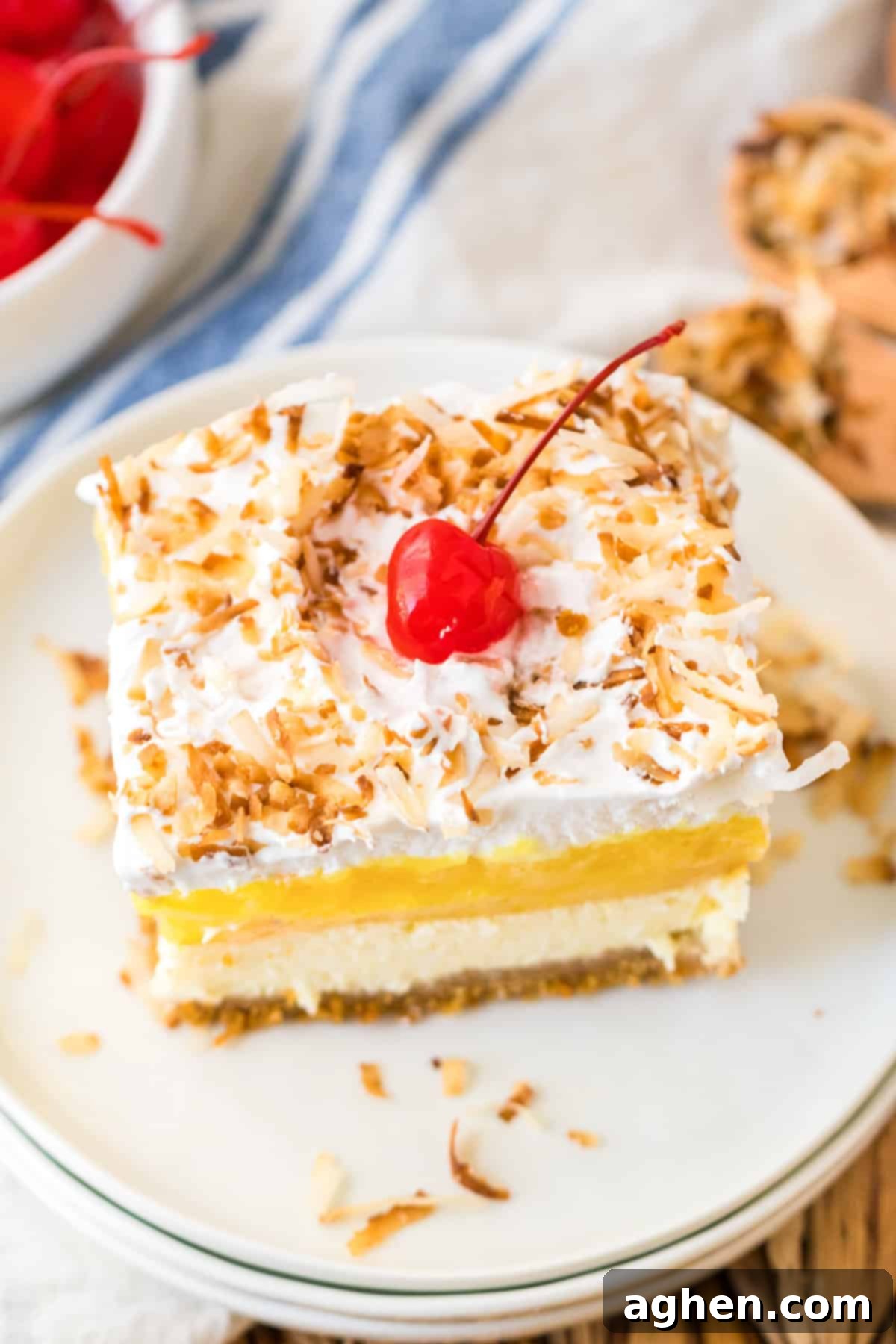 Pina Colada Dream 10 Pineapple Coconut Layered Dessert with layers of creamy pineapple filling, coconut cheesecake, and whipped topping on top of a buttery graham cracker crust.