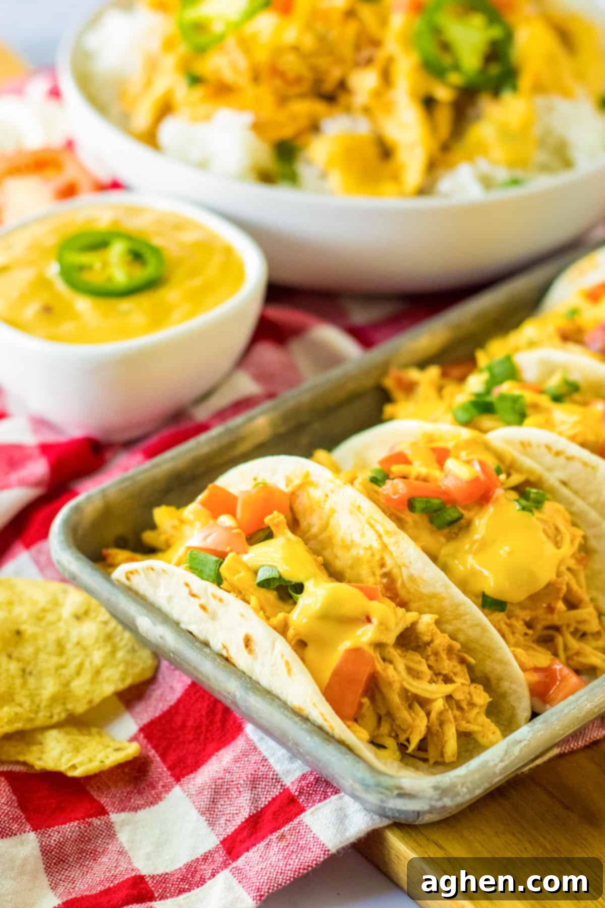 Slow cooker queso chicken tacos served in warm flour tortillas on a festive serving tray, garnished with fresh cilantro and lime wedges.