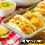 Slow cooker queso chicken tacos in flour tortillas on a serving tray.