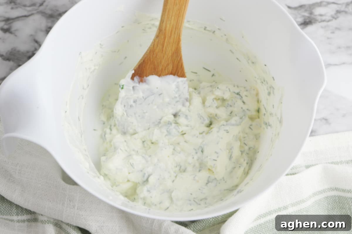 Dill dip in a bowl with a wooden spoon.