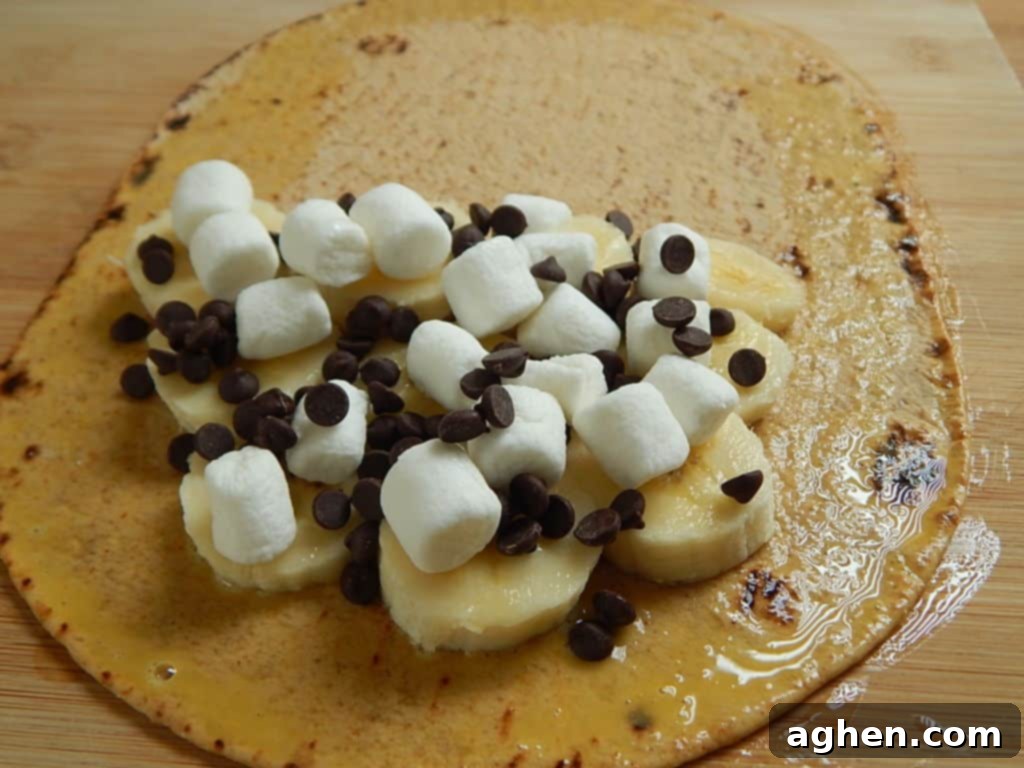 Half of a Flatout bread filled with banana slices, mini marshmallows, and chocolate chips.