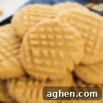 Batch of cake mix peanut butter cookies with criss-cross pattern pressed in the top.