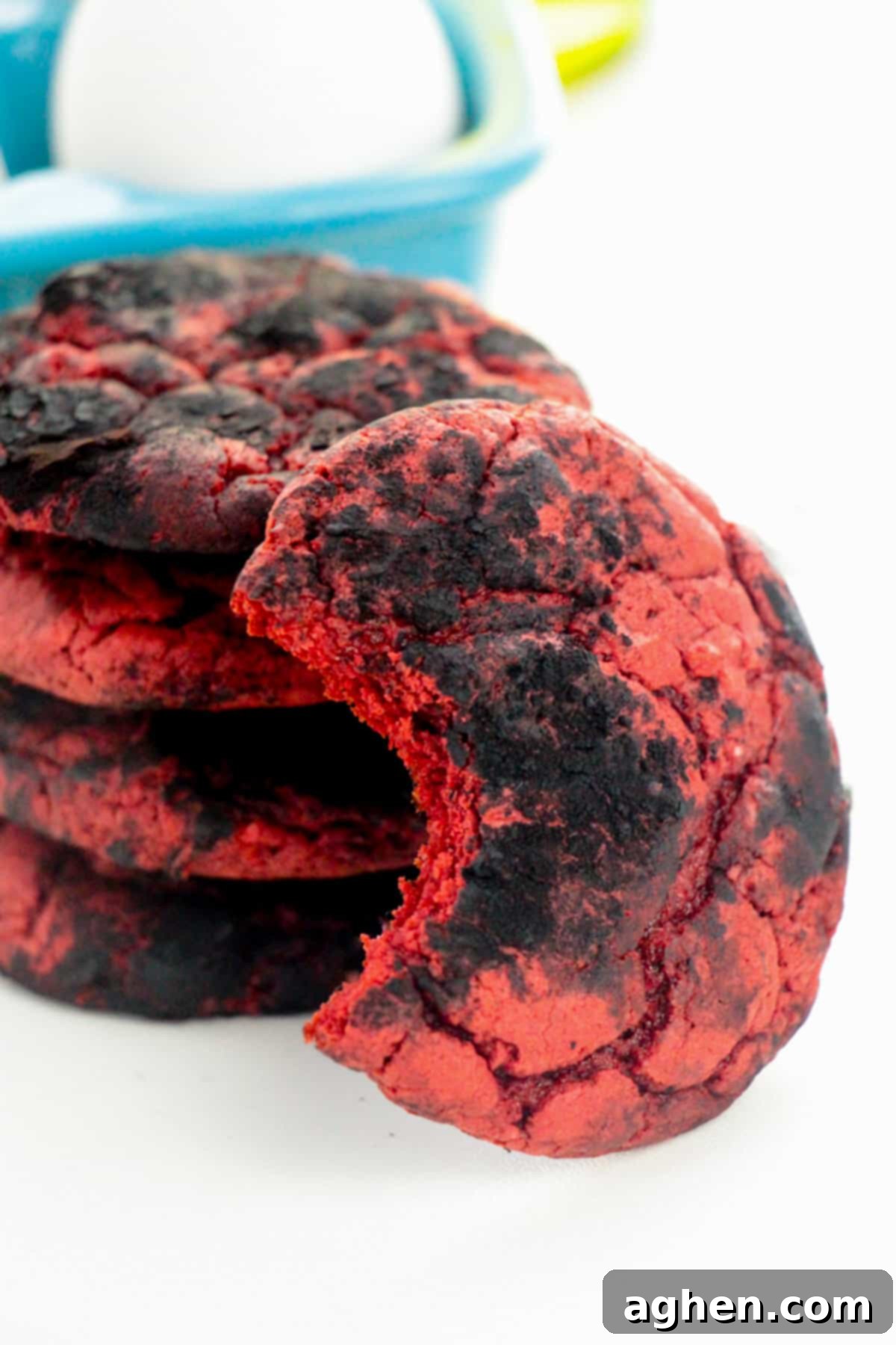 Devil's Delights 6 A single red velvet Brimstone Cookie coated with black cocoa powder for a crinkle effect. A bite has been taken, revealing the soft, deep red interior of the cake mix cookie.