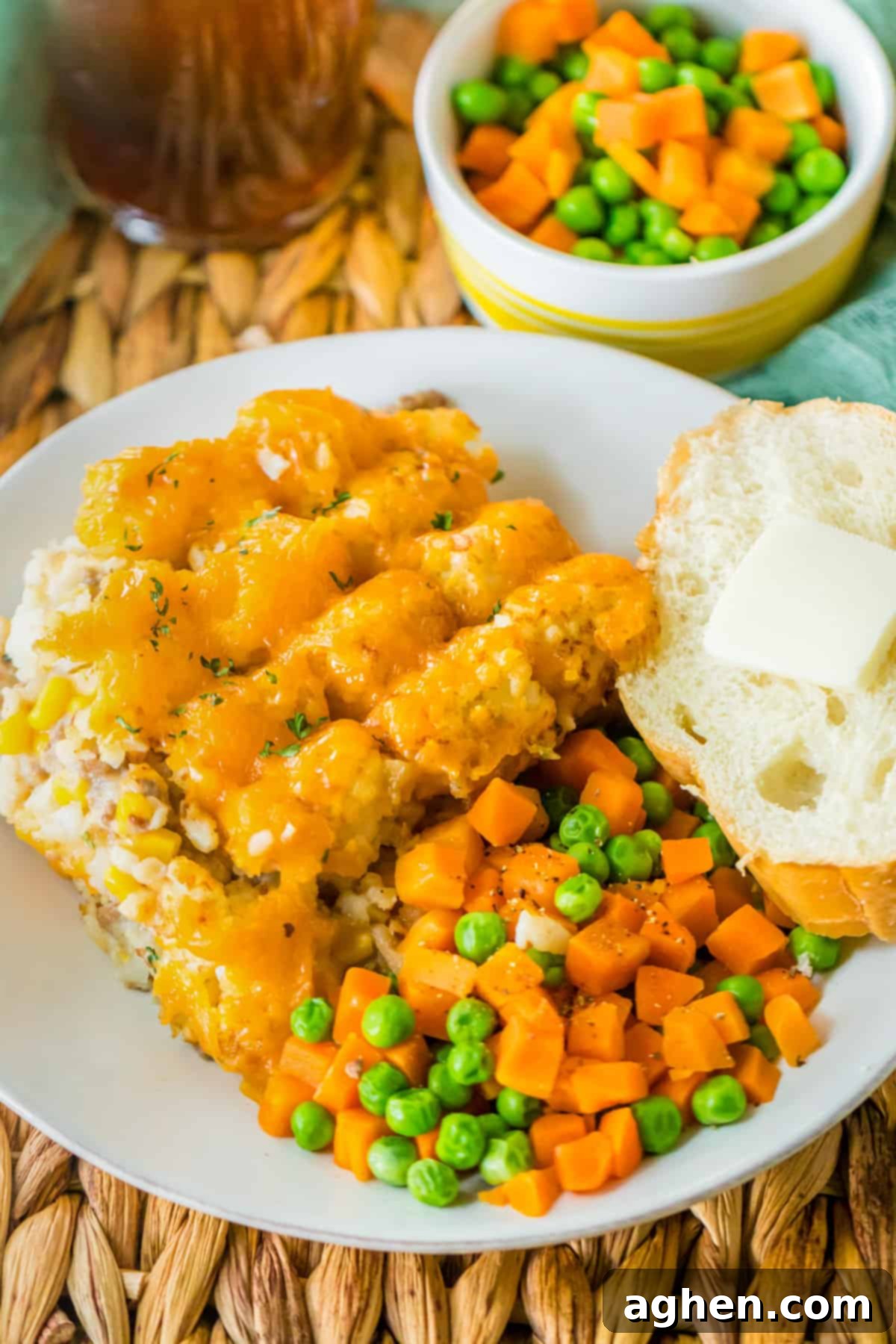 Effortless Tater Tot Comfort 3 Ground Beef tater tot casserole served with peas, carrots, and buttered bread.