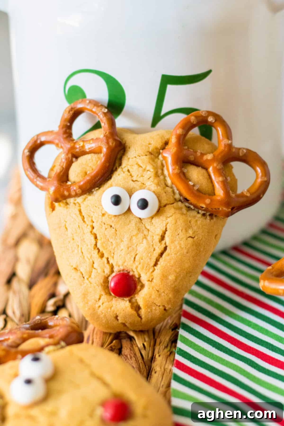 Peanut butter reindeer cookie with pretzel antlers, red M&M nose, and candy eyeballs.