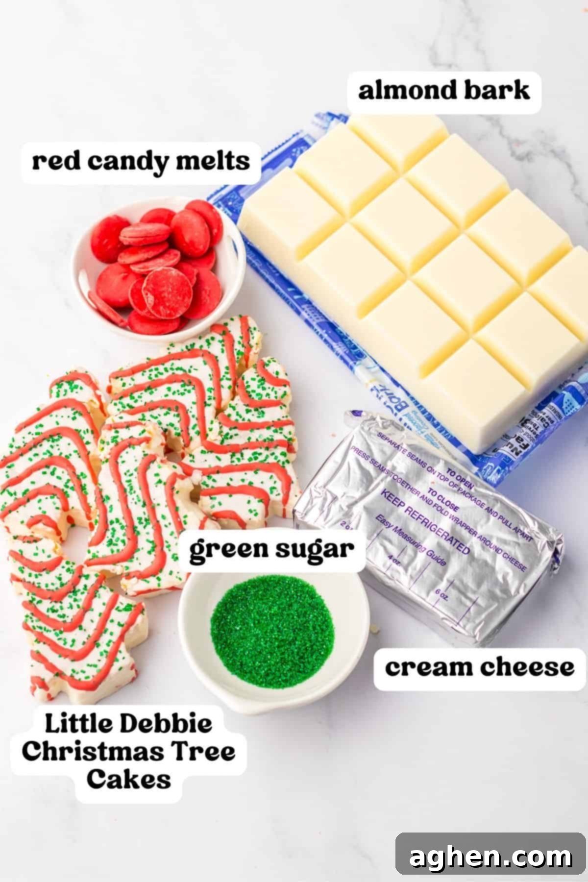 A collection of ingredients for Christmas cake truffles, including vibrant red candy melts, creamy white almond bark, festive green sugar, softened cream cheese, and a stack of iconic Little Debbie Christmas Tree Cakes.