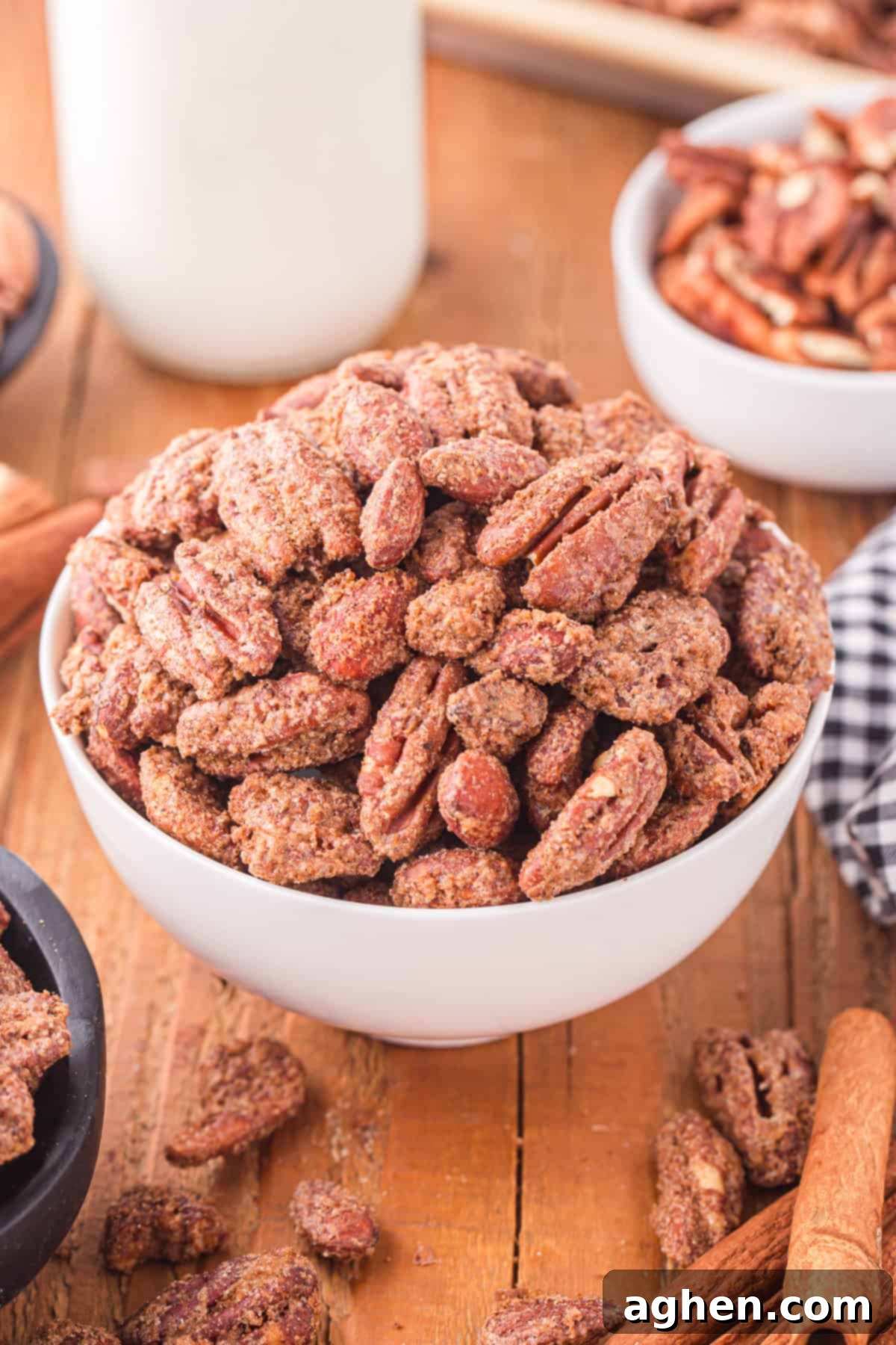 Candied pecans and almonds in a white bowl, glistening with sugar coating.