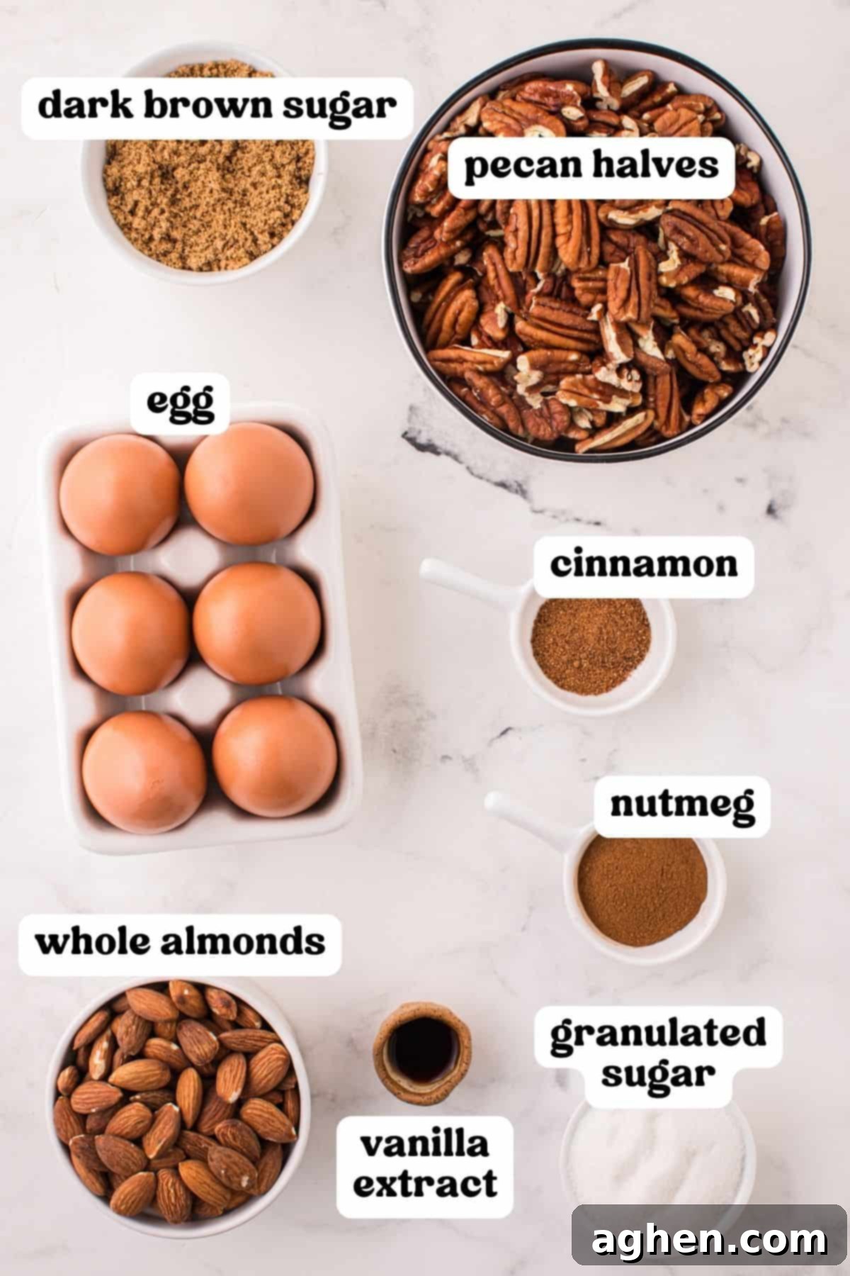 A collection of ingredients for candied nuts: dark brown sugar, whole almonds, pecan halves, egg, cinnamon, nutmeg, vanilla extract, and granulated sugar.