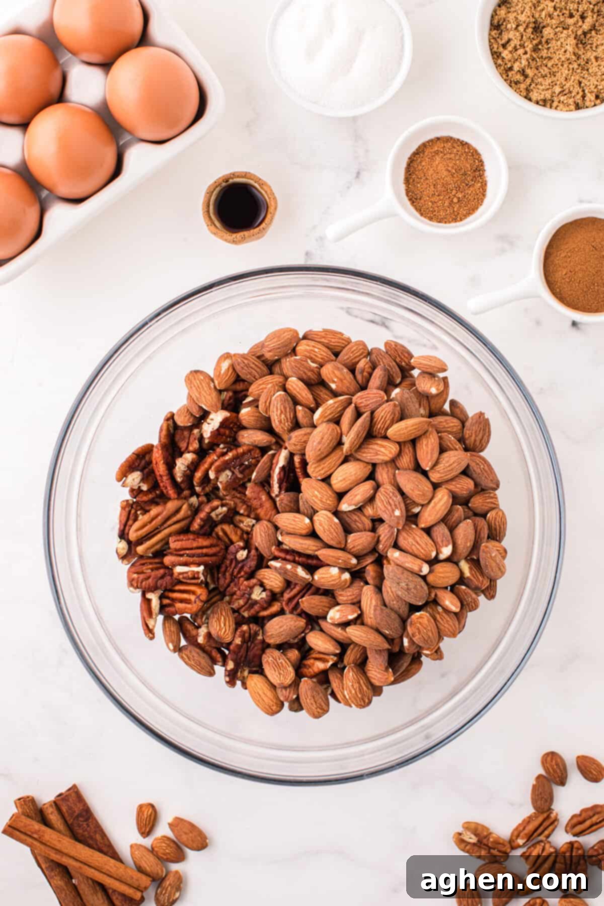 Raw almonds and pecan halves in a glass mixing bowl, ready for the next step.