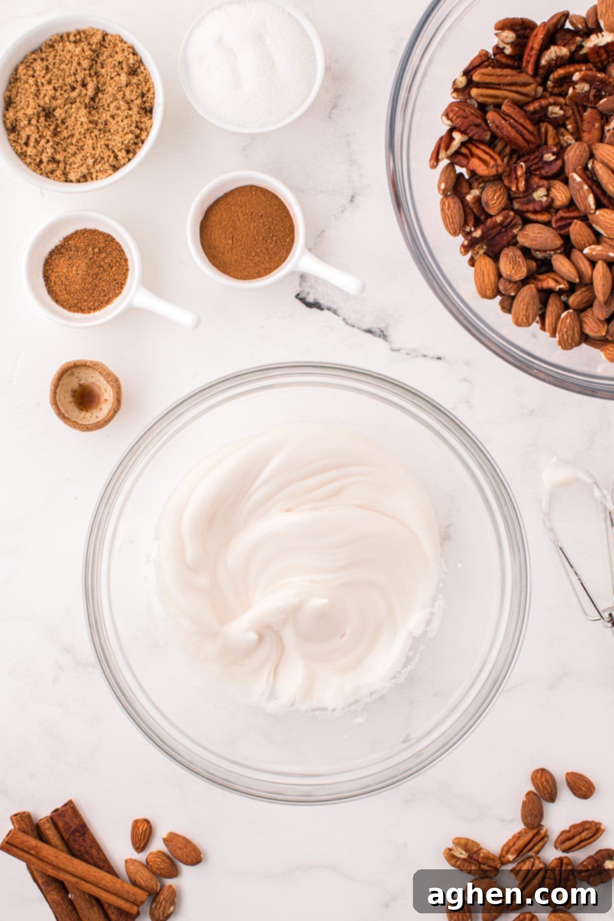 Whipped egg white with vanilla extract in a glass bowl, prepared for coating nuts.