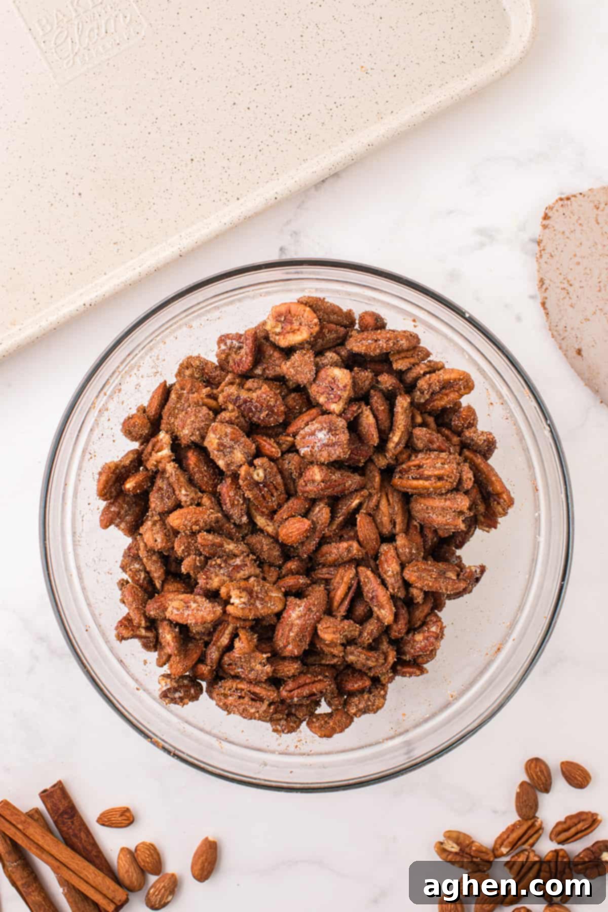 Almonds and pecans fully coated in the sugar and spice mixture within a mixing bowl.