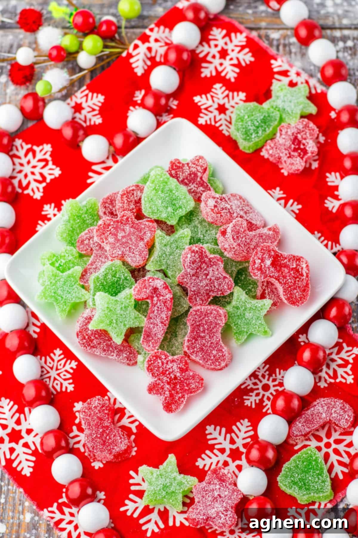 Christmas gumdrop candy on a square white plate surrounded by red and white holiday decor and additional gumdrop candies.