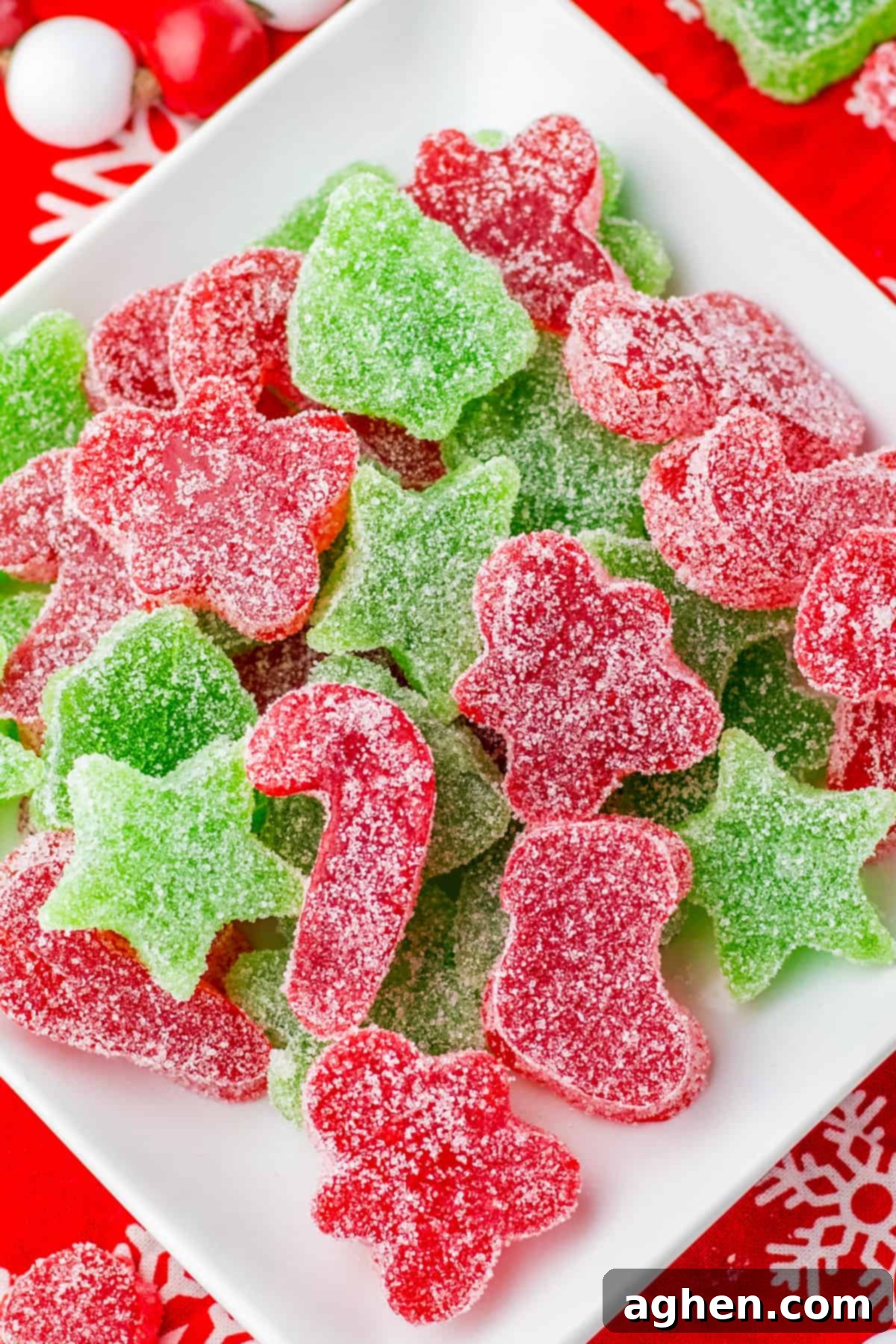 Red and green Christmas gumdrops cut into festive shapes piled on a white plate.