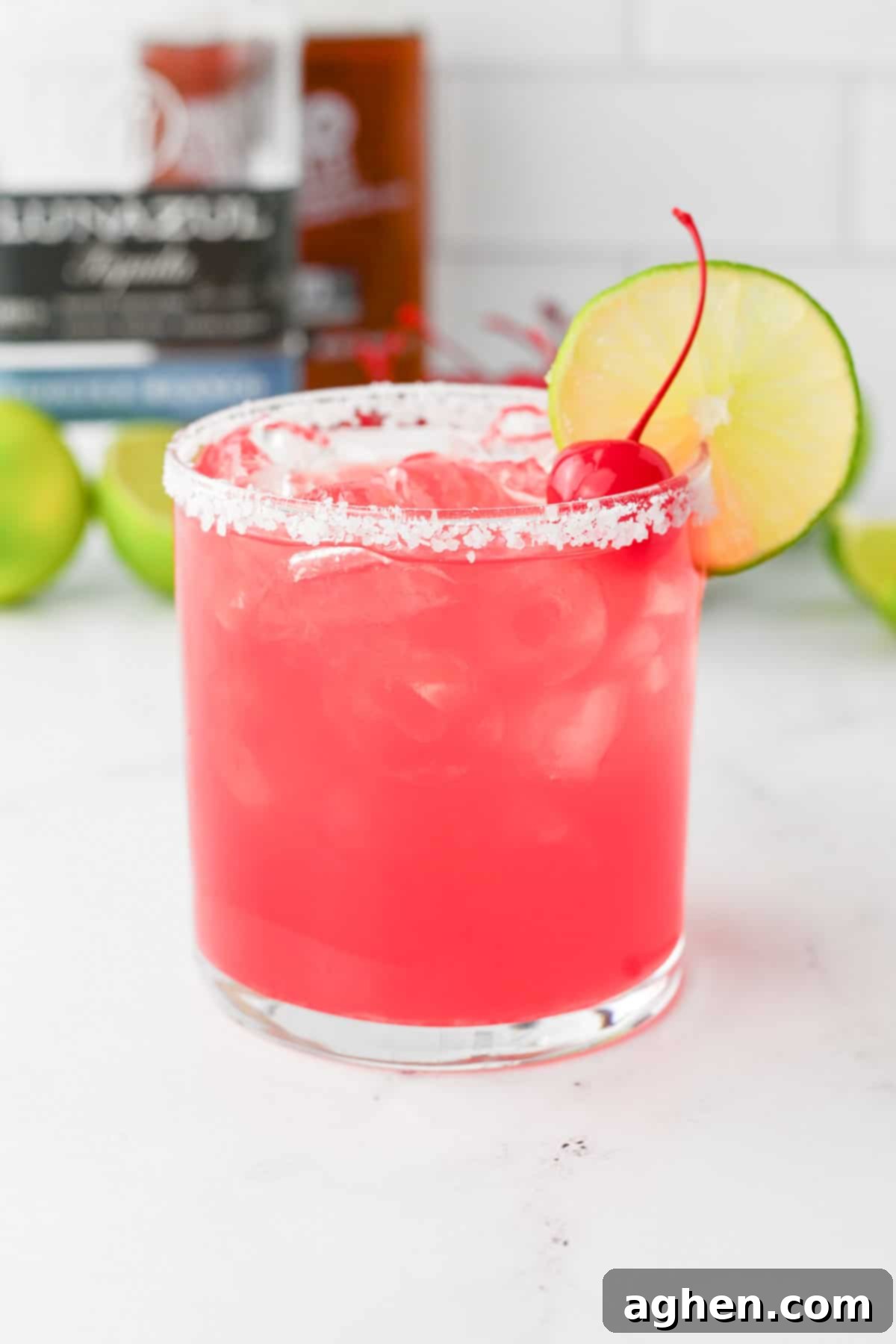 Blush Margarita 2 Pink Margarita with salted rim and lime wheel and cherry for garnish.