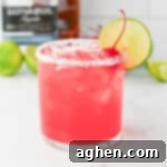 Blush Margarita 8 Pink Margarita drink in a rocks glass with salted rim and lime wheel and maraschino cherry garnish.