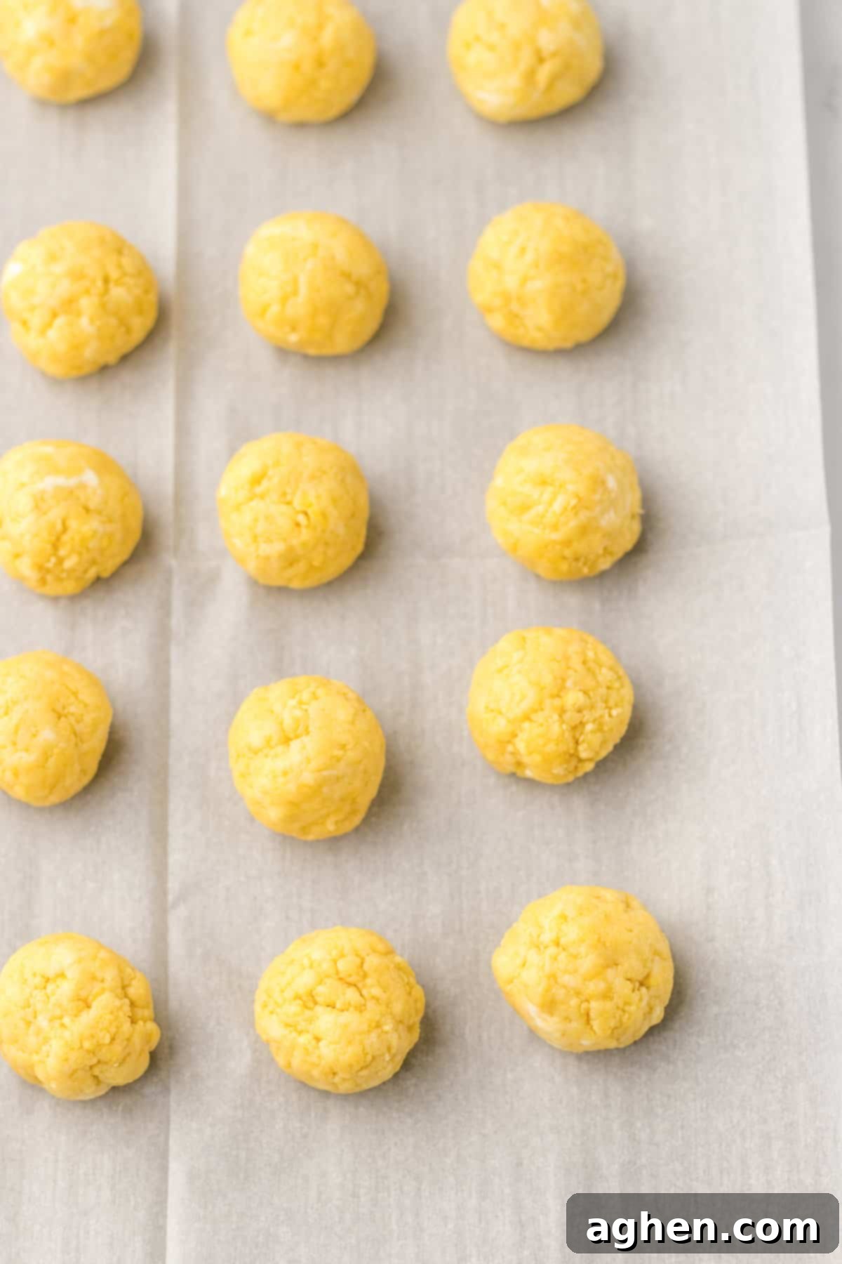 Perfectly rolled lemon Oreo cookie balls resting on a parchment-lined sheet pan, ready for chilling and dipping.