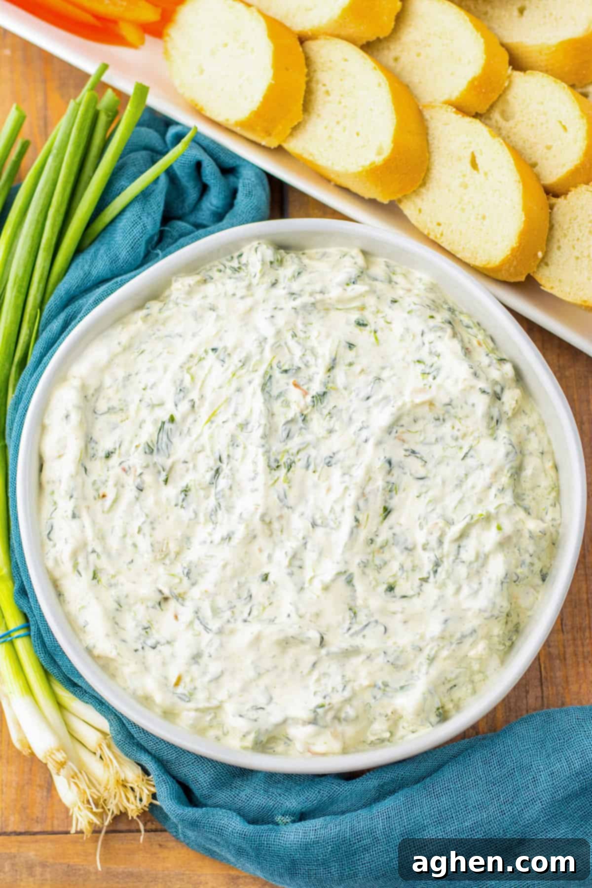 Creamy Knorr Spinach Dip 2 Classic Knorr spinach dip in a white serving bowl next to a tray of bread and veggies for dipping, showcasing a perfect party appetizer.