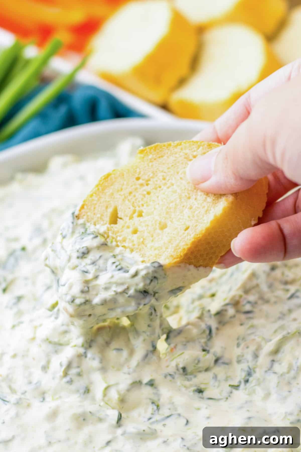 Creamy Knorr Spinach Dip 6 A piece of bread being dipped into a bowl of cold Knorr spinach dip, ready to be enjoyed.