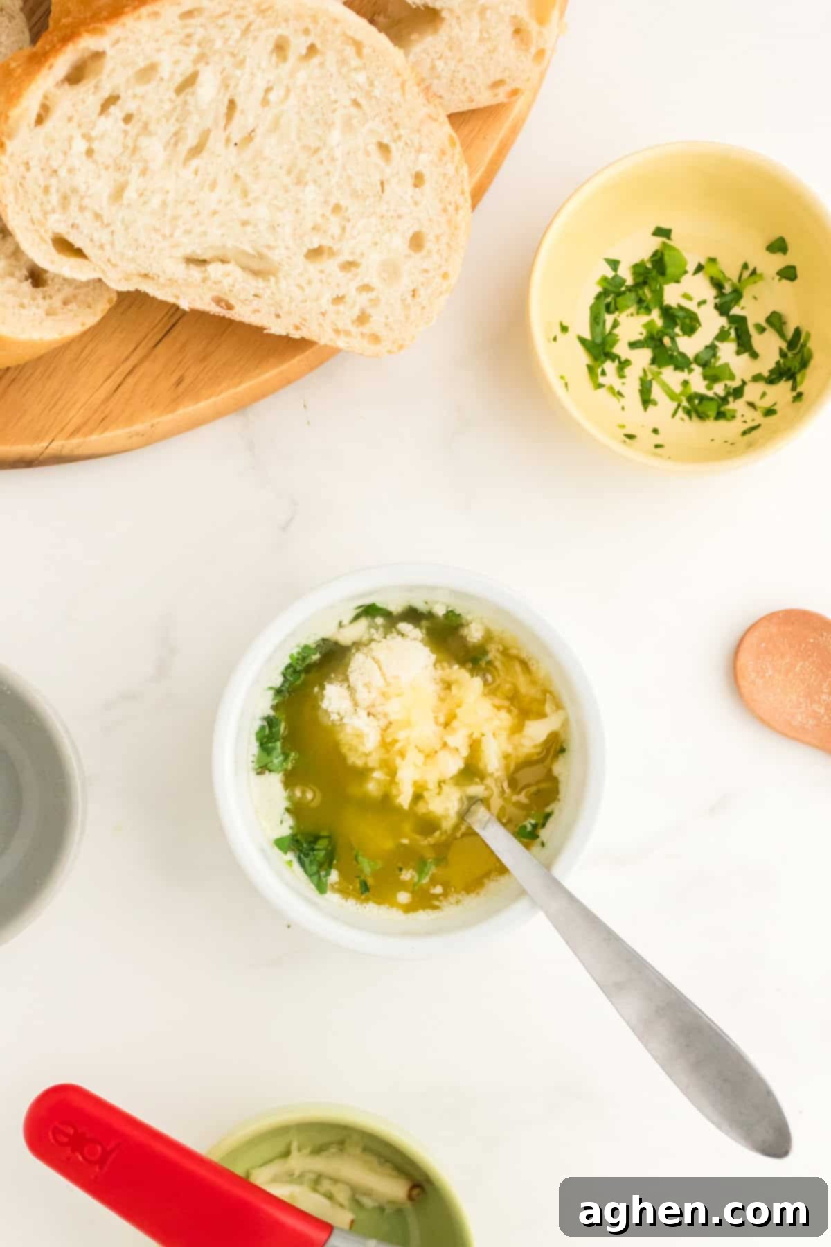 Melted butter in a small bowl with garlic, parsley, Parmesan cheese, and a spoon.