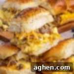 Sweet & Savory Hawaiian Breakfast Bake 12 3 Sausage egg and cheese Hawaiian Roll Breakfast Sliders stacked on top of one another with more in the background, a perfect breakfast.