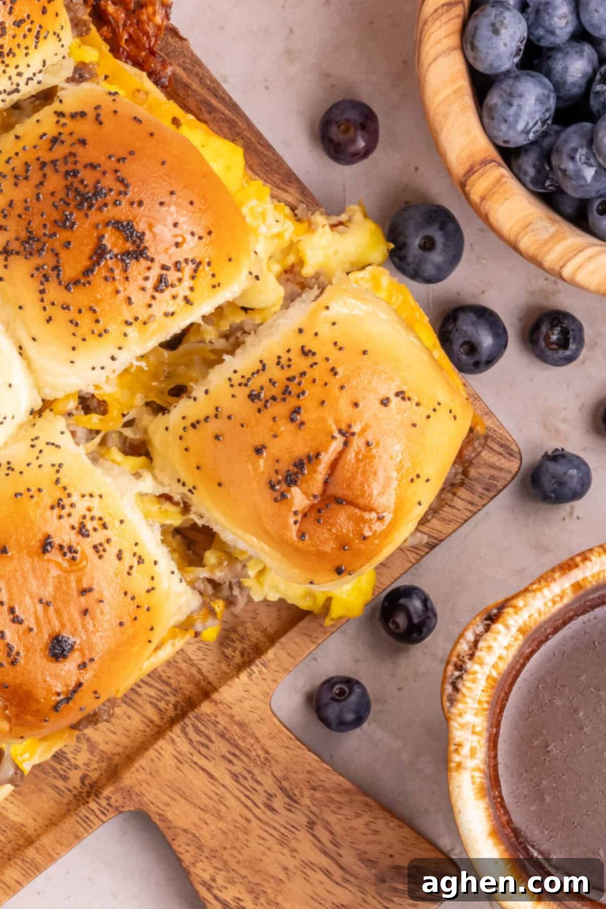 Sweet & Savory Hawaiian Breakfast Bake 10 Close-up of perfectly baked King's Hawaiian Breakfast Sliders, filled generously with scrambled eggs, savory ground sausage, and melted cheese, beautifully served with a vibrant side of fresh blueberries, making for an appetizing breakfast.