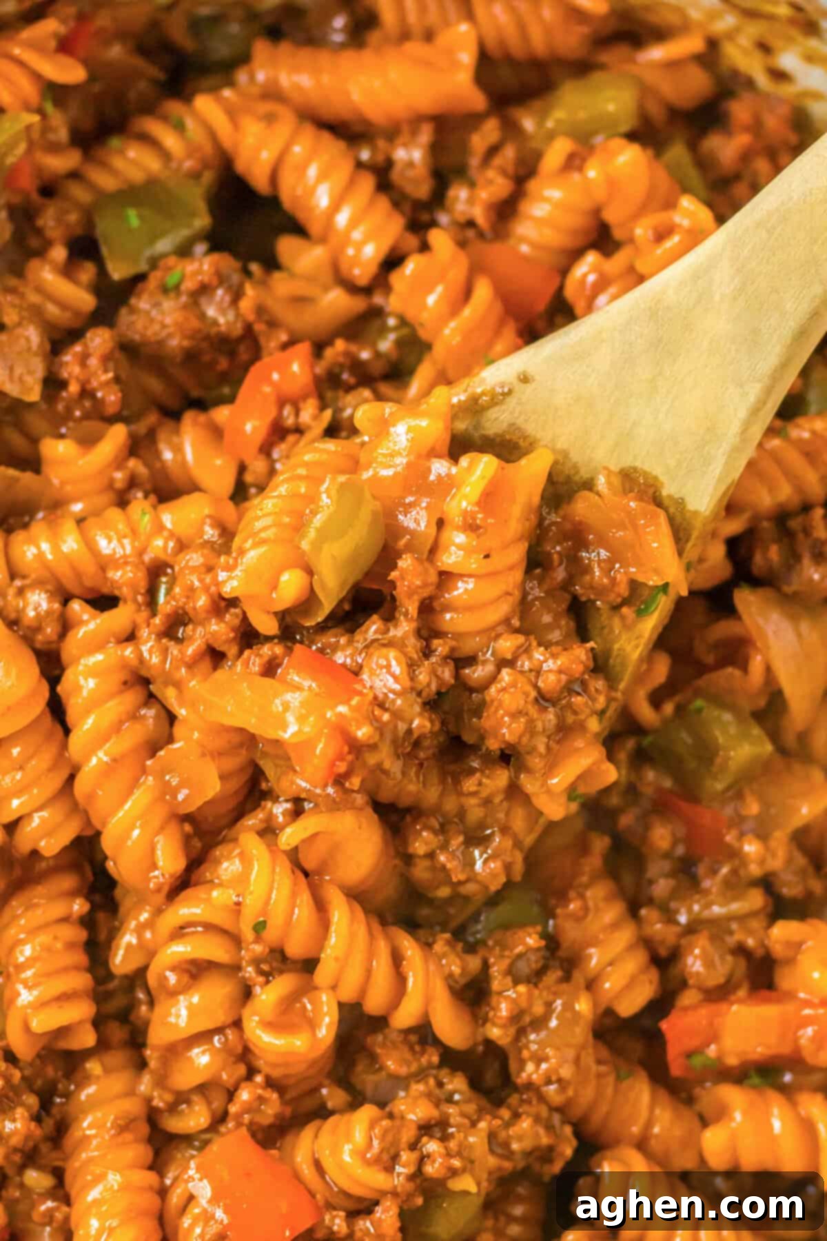 Hearty Sloppy Joe Pasta 3 Sloppy Joe pasta with ground beef, vibrant bell peppers, and onions simmering in a large skillet, stirred with a wooden spoon.