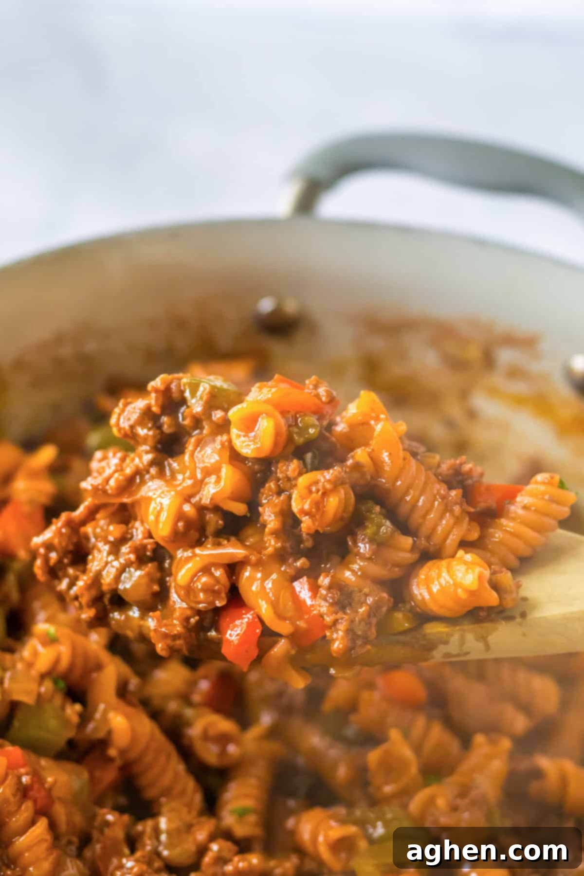 Hearty Sloppy Joe Pasta 7 A spoonful of hot, saucy One Pot Sloppy Joe Pasta being lifted from a skillet, showcasing the rotini and rich sauce.