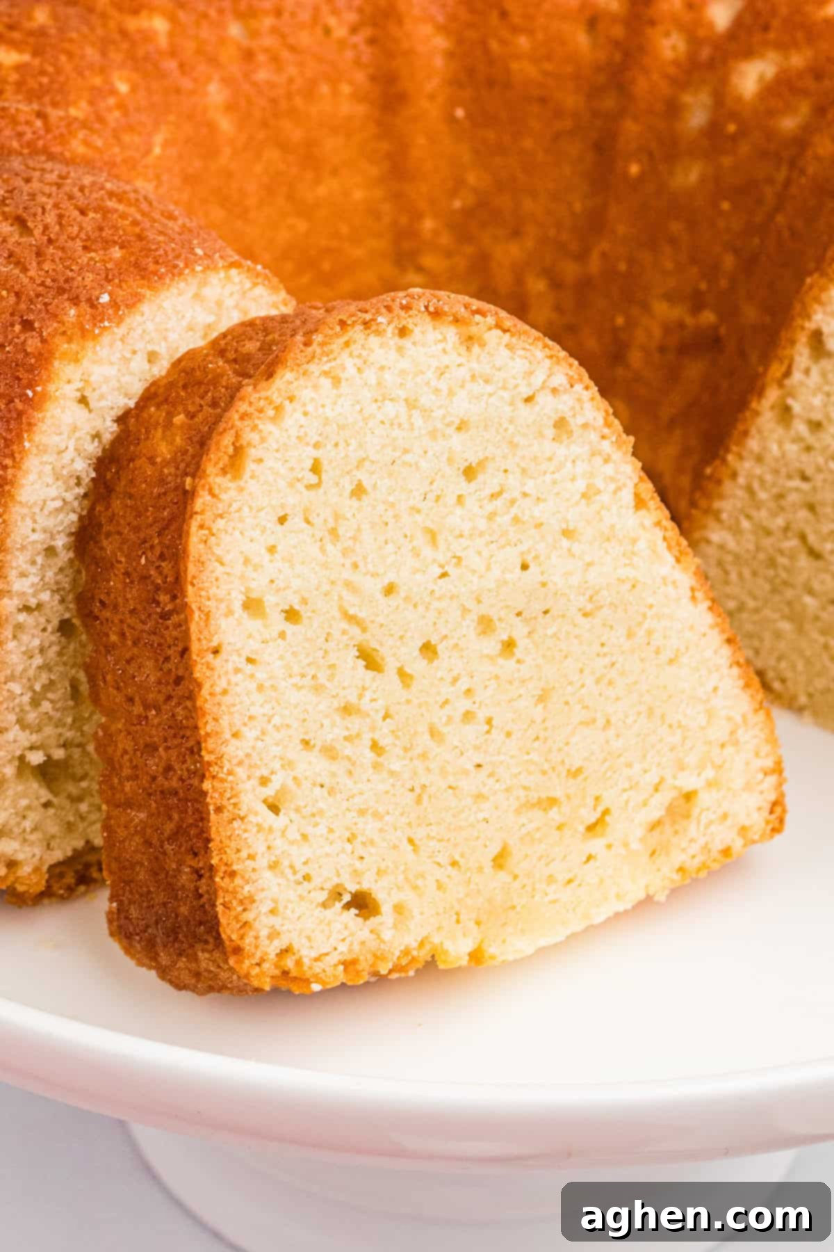 Slice of sour cream pound cake leaning on remaining pound cake.