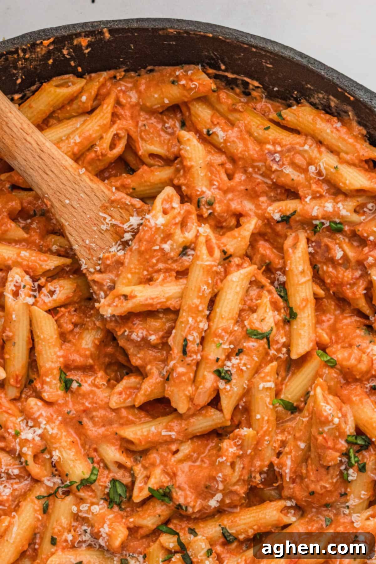 Creamy penne alla vodka in large skillet with wooden spoon.