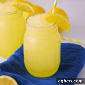 Frozen Lemonade Bliss 7 Frozen lemonade slushies garnished with slice of lemon and served in mason jars with yellow striped straws.