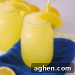Frozen Lemonade Bliss 8 Frozen lemonade slushies garnished with slice of lemon and served in mason jars with yellow striped straws.