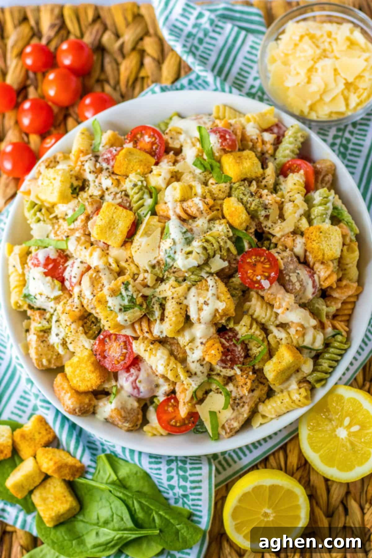 Chicken Caesar Pasta Salad with crisp romaine lettuce, halved cherry tomatoes, grated Parmesan cheese, crunchy croutons, and a generous drizzle of creamy Caesar dressing.