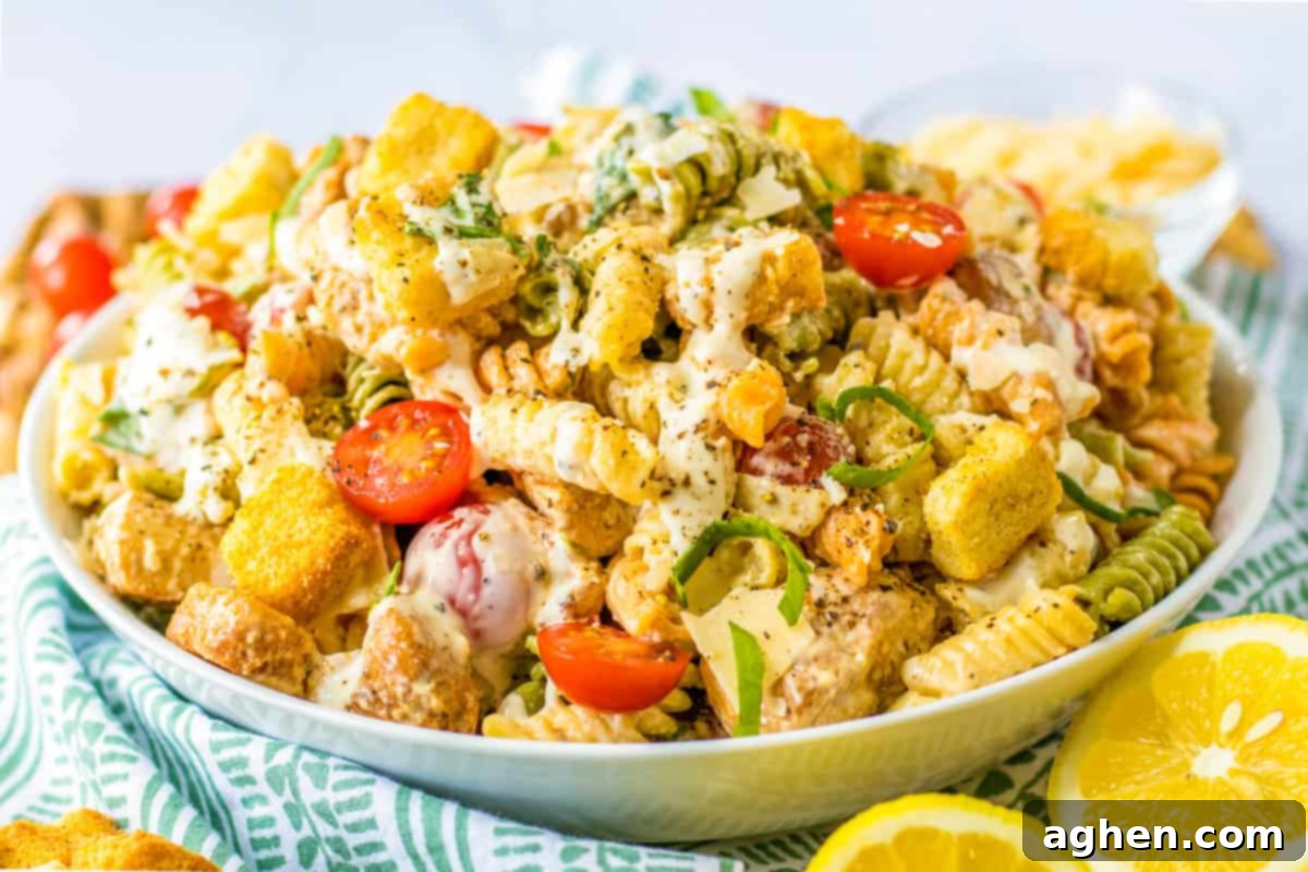 A top-down view of Caesar pasta salad with chicken in a white bowl, ready to be served.