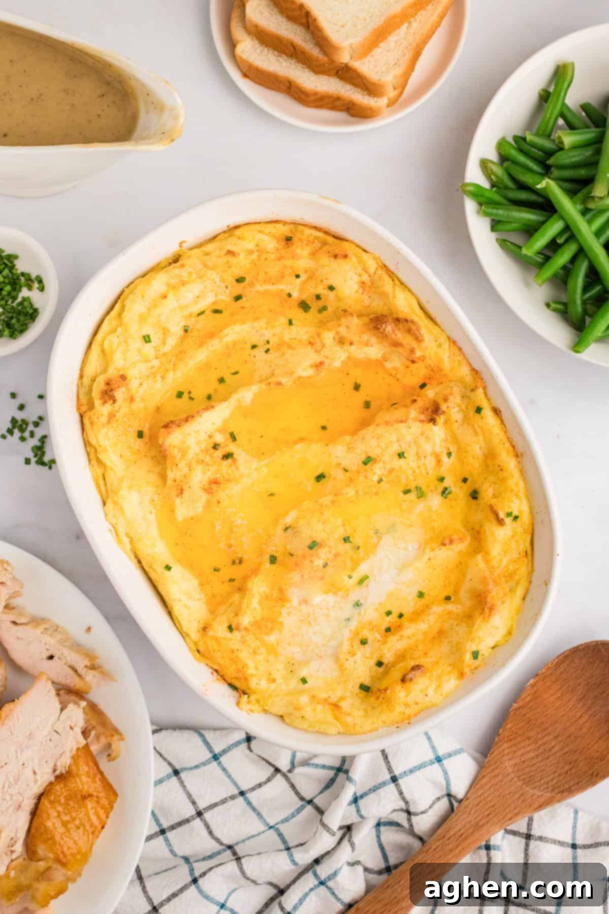 Party potatoes in casserole dish surrounded by a festive holiday meal including roasted turkey, vibrant green beans, and rich brown gravy. The setting is warm and inviting.