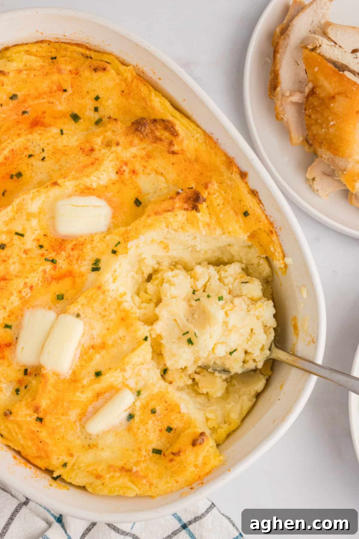Cream Cheese Baked Mashed Potatoes, beautifully golden-brown and topped with a sprinkle of paprika, melted butter, and freshly chopped chives, ready to be served.